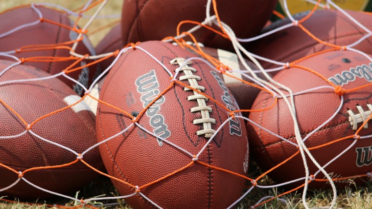 American footballs under orange and white netting